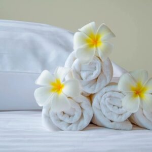 A pile of rolled up towels with flowers on top.