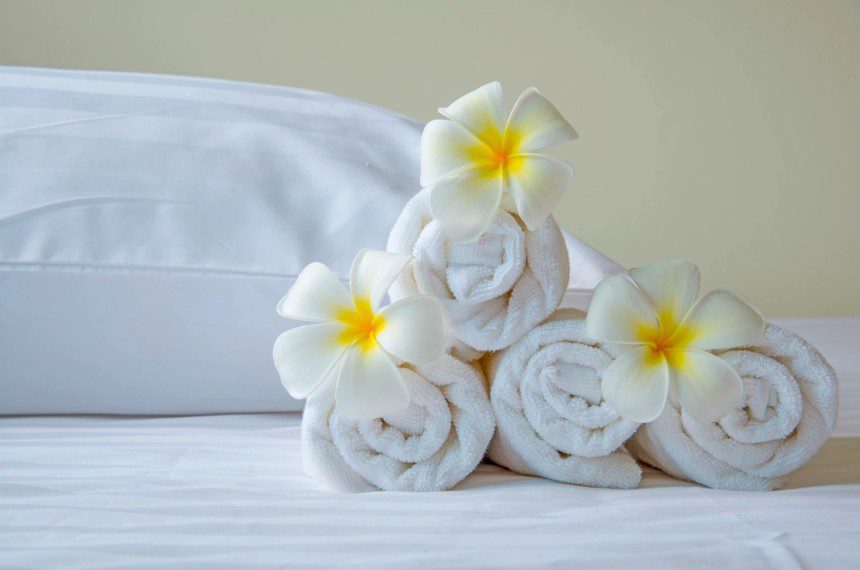 A pile of rolled up towels with flowers on top.