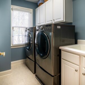 A laundry room with two machines and cabinets.