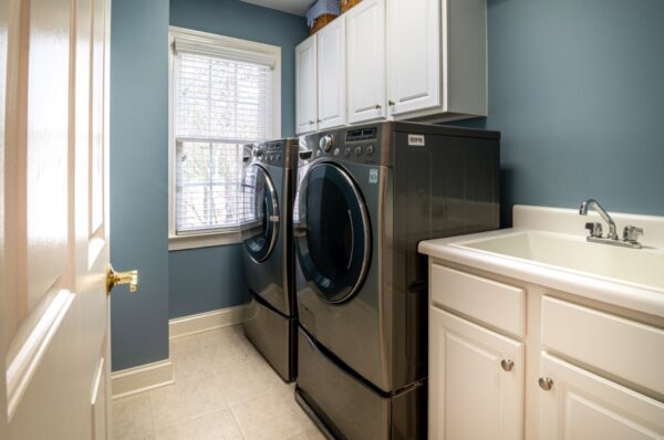 A laundry room with two machines and cabinets.