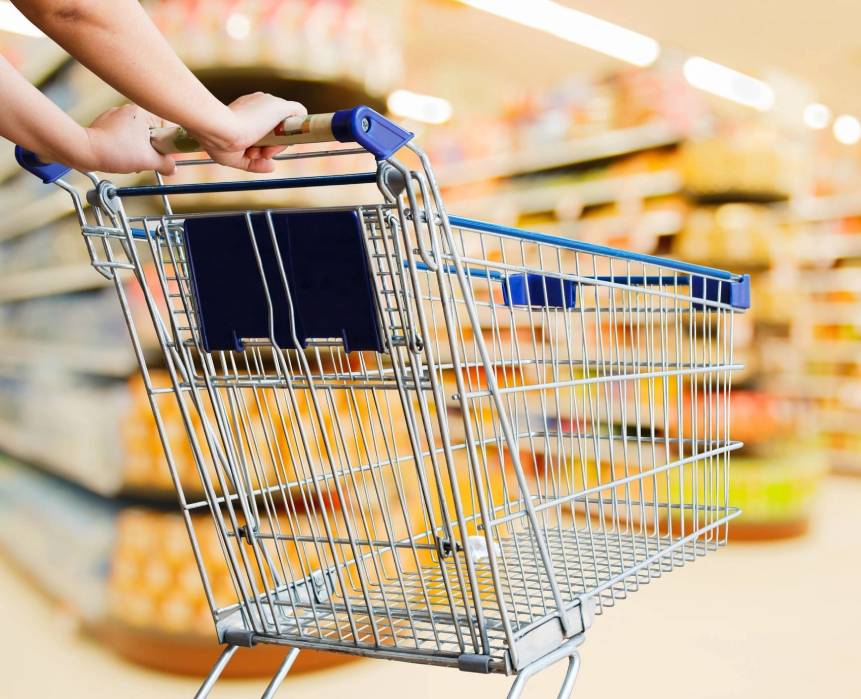 A person pushing a shopping cart in the aisle of a store.